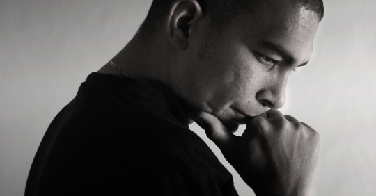 Man pondering with hand on chin, side profile, image in black and white